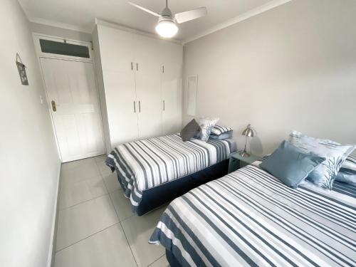 two beds in a small room with white cabinets at Anchored Inn II - A Slice of Heaven in Beautiful Scottburgh in Scottburgh