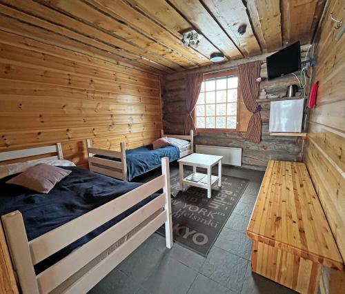 a bedroom with two beds in a wooden cabin at Hotelli Vuorikelo in Muurame