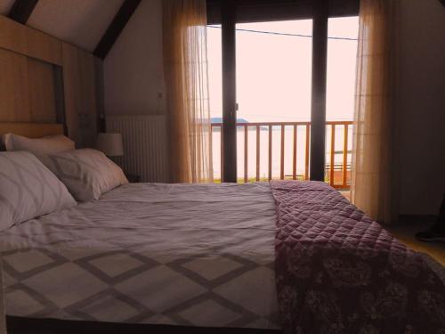 a bedroom with a bed with a view of a balcony at The Lake House in Mikrolímni