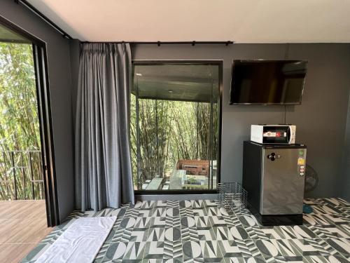 1 dormitorio con 1 cama, TV y balcón en Ton Pling Khao Lak Villa en Khao Lak