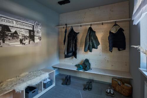 een kamer met een houten muur met jassen en schoenen bij AHORN7 in Reit im Winkl
