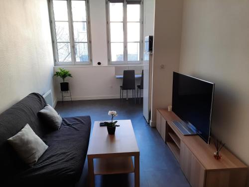 un salon avec un canapé et une télévision dans l'établissement Grand T1 au calme - Dijon centre, à Dijon