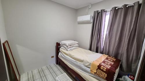 a small bedroom with a bed and a window at Apto a poucos metros do mar in Matinhos