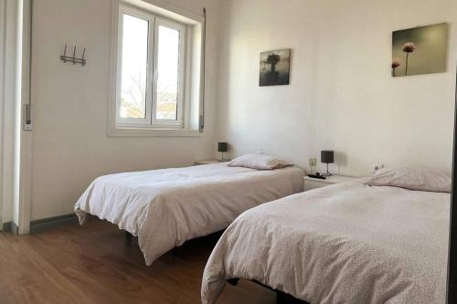 Cette chambre blanche dispose de 2 lits et d'une fenêtre. dans l'établissement Helena House, à Senhora da Hora