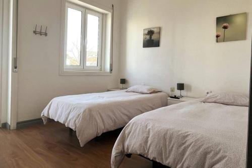 two beds in a white room with a window at Helena House in Senhora da Hora