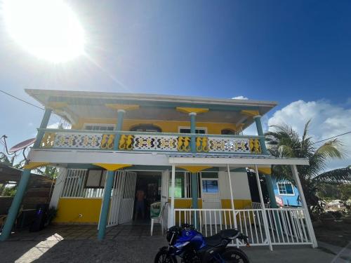 une moto bleue garée devant une maison jaune dans l'établissement Posada buena vista al mar, à Île de la Providence