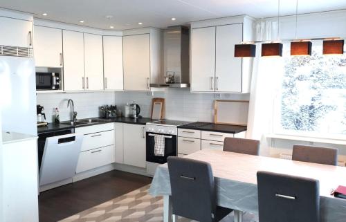 a kitchen with white cabinets and a table with chairs at Ailo in Inari