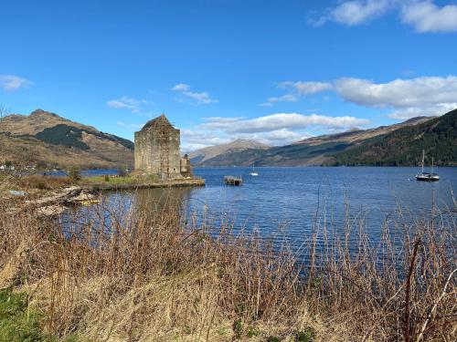 a castle on a island in a body of water at the waterside - carrick castle - loch goil in Carrick