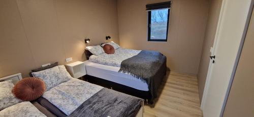 a small bedroom with two beds and a window at Black Beach Farm in Vík