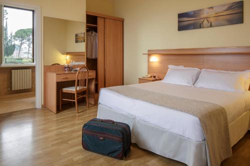 ペルージャにあるHotel Sacro Cuoreのベッドとスーツケース付きのホテルルーム