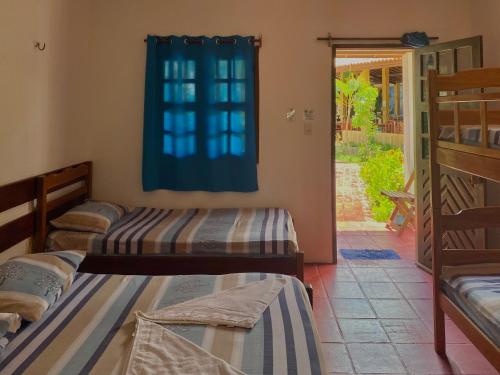 três camas num quarto com uma janela em Pousada Paraiso Verão em Jiloca de Jericoacoara