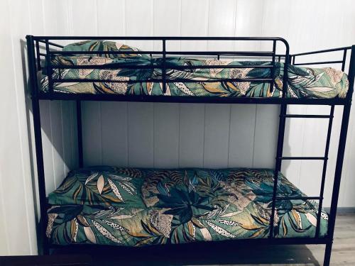 a triple bunk bed with a flower patterned blanket at Maison a Bourg- Murat proche de la cité du volcan in La Plaine des Cafres