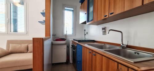 una cucina con lavandino in acciaio inossidabile e divano di Casa SantaBarbara a Marina di Ragusa