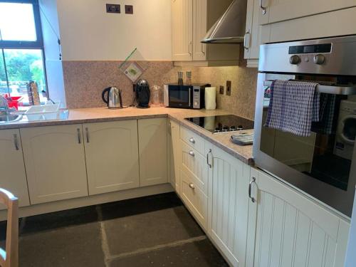 a kitchen with white cabinets and a stove top oven at Sea View ,Cottage2 Dunnetbay accommodation in Castletown