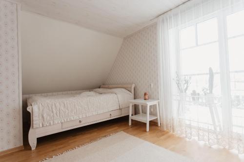 a white bedroom with a bed and a window at Vase Holiday Home in Tartu