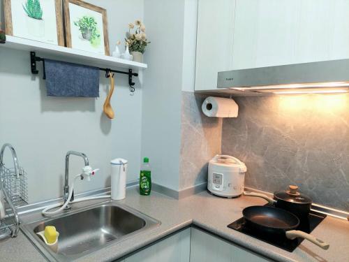 La cocina está equipada con fregadero y fogones con sartén. en J'Stay Seaview Suite Jesselton Quay Kota Kinabalu en Kota Kinabalu