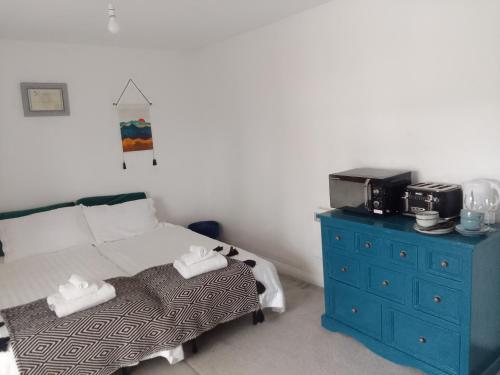 a bedroom with a bed with a blue dresser and a microwave at Beech House 20 minute walk to Airport in Bristol