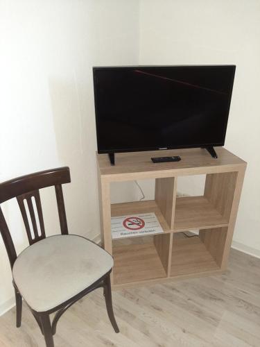 a tv sitting on top of a wooden stand with a chair at Gasthof & Pension Zum Saalestrand in Bad Dürrenberg