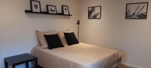 um quarto com uma cama com almofadas pretas em Studio avec jardin et stationnement gratuit à Rouen em Rouen