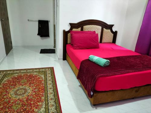 1 dormitorio con cama con sábanas rosas y alfombra en Sofea Homestay, en Batu Rakit
