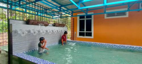dos niños están jugando en una piscina en Sofea Homestay, en Batu Rakit