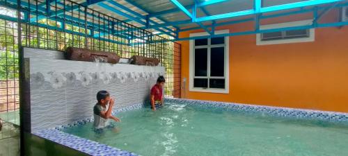 two children are playing in a swimming pool at Sofea Homestay in Batu Rakit