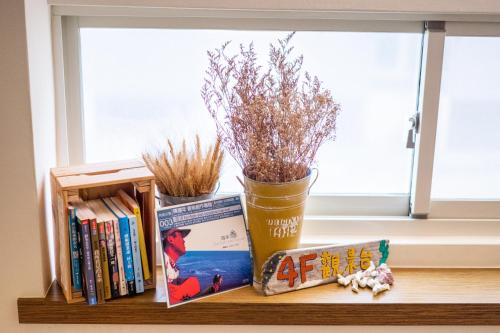 a shelf with books and flowers and a window at THEDAY B&B in Magong