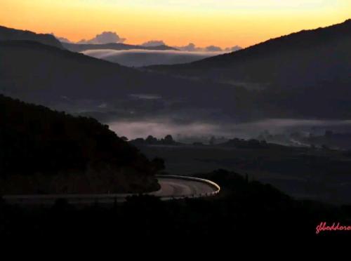 a winding road in the mountains with the sun setting at Sa domu 'eccia in Urzulei