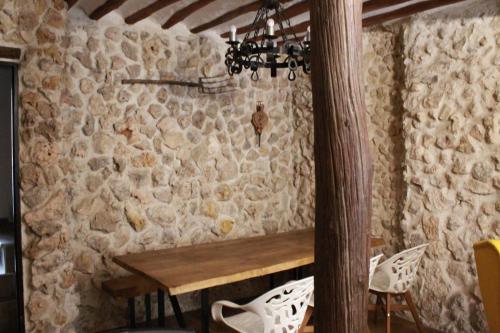 eine Steinmauer mit einem Holztisch und einem Kronleuchter in der Unterkunft Casa Rural Los Agüelos in Mazuecos