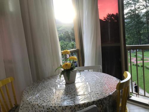 ein Esstisch mit einer Vase mit Blumen darauf in der Unterkunft Loft Reserva do Sahy - Mangaratiba in Mangaratiba