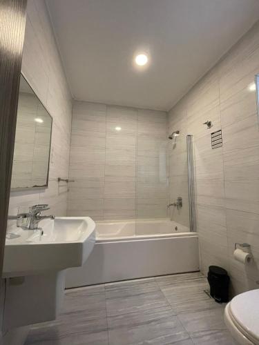 a bathroom with a tub and a sink and a toilet at NSTS Manche Residence in Il-Gżira