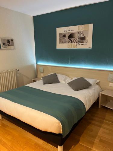 uma cama grande num quarto com uma parede azul em Etesia em Feurs