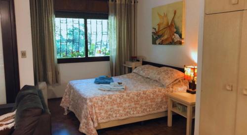 a bedroom with a bed and a couch and a window at CASA GOLDONI GRAMADO 4 Quartos in Gramado
