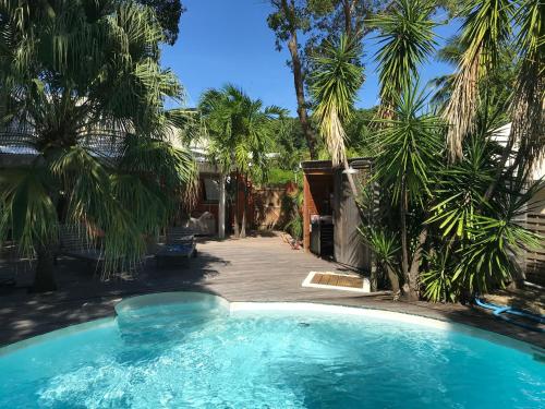 a swimming pool in a yard with palm trees at Maison Saint Exupéry avec piscine in Le François