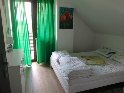 a bedroom with a bed with green curtains and a window at Dom nad jeziorem - MAZURY in Szczytno