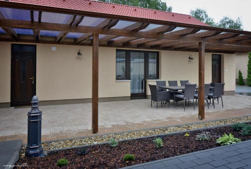 a patio with a table and chairs under a wooden pergola at Vincze Vendeghaz in Kiskunhalas