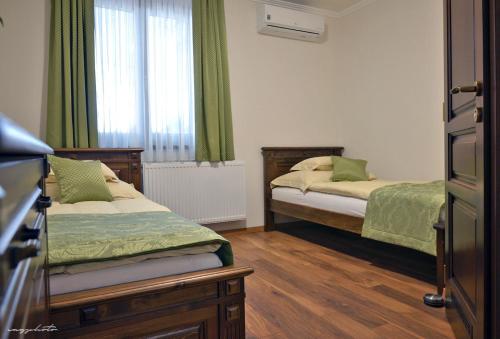 um quarto com 2 camas e uma janela com cortinas verdes em Vincze Vendeghaz em Kiskunhalas