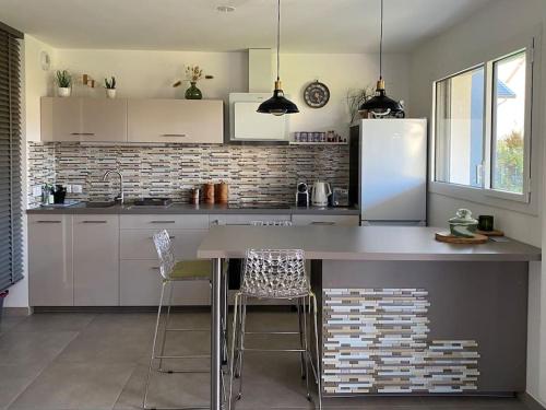 a kitchen with a counter with chairs and a refrigerator at Appartement neuf au calme proche du lac in Saint-Jorioz