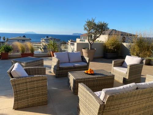 a patio with wicker chairs and couches on a roof at Penthouse Le Isole in Marsala