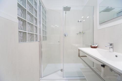 uma casa de banho branca com um chuveiro e um lavatório. em Eugenia e Donato em Nápoles