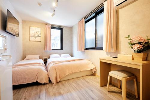 two beds in a room with a desk and two windows at New Designed apart ment Shin-Okubo Sta 3 min walk in Tokyo