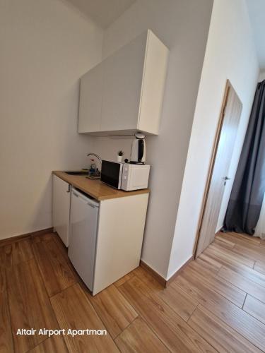 a small kitchen with a refrigerator and a microwave at Altair Airport Apartman in Vecsés