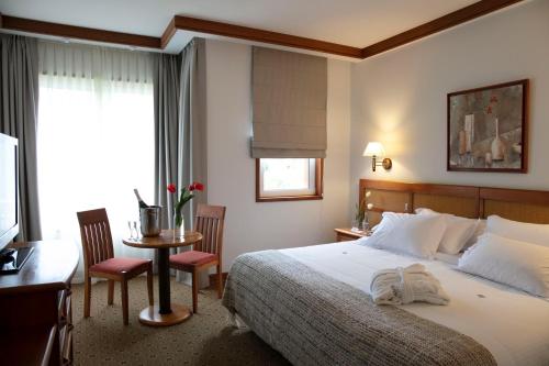 um quarto de hotel com uma cama, uma mesa e cadeiras em Hotel Termas Puyehue Wellness & Spa Resort em Puyehue