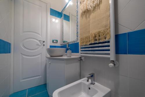 baño azul y blanco con lavabo y espejo en Ravello Dream Charming House, en Scala
