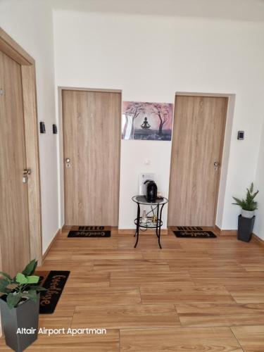 a room with three wooden doors and a table at Altair Airport Apartman in Vecsés