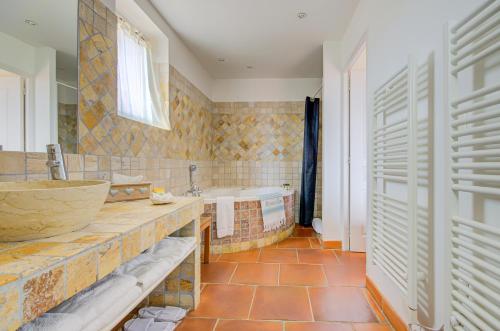 a bathroom with a tub and a sink and a bath tub at Omma, Le Clos de la Glycine in Roussillon