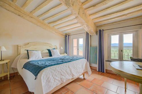 une chambre avec un lit, une table et des fenêtres dans l'établissement Omma, à Roussillon