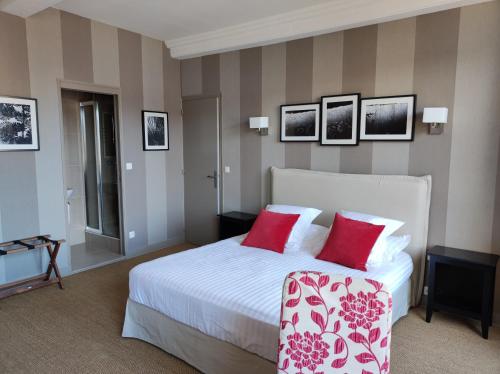 a bedroom with a large white bed with red pillows at Mansion Victorine in Honfleur