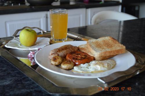 a plate of breakfast food on a tray with an apple and orange juice at Glorious Home Bed & Breakfast in Mochudi