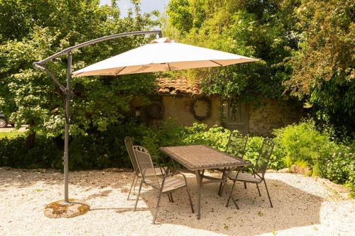 a table and chairs under an umbrella in a yard at La Maison au Vert in Melincourt